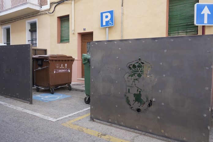 Contenedores con los parapetos que intentan ocultarlos sobre una plaza hasta ahora reservada para minusválidos. (Foto: PSOE)