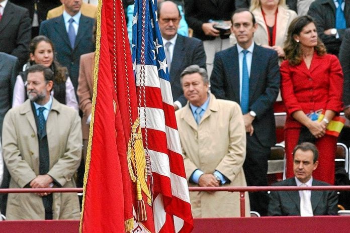 Una imagen histórica la de Luis de Grandes, de pie, y Rodríguez Zapatero, sentado, al paso de la bandera de los Estados Unidos.